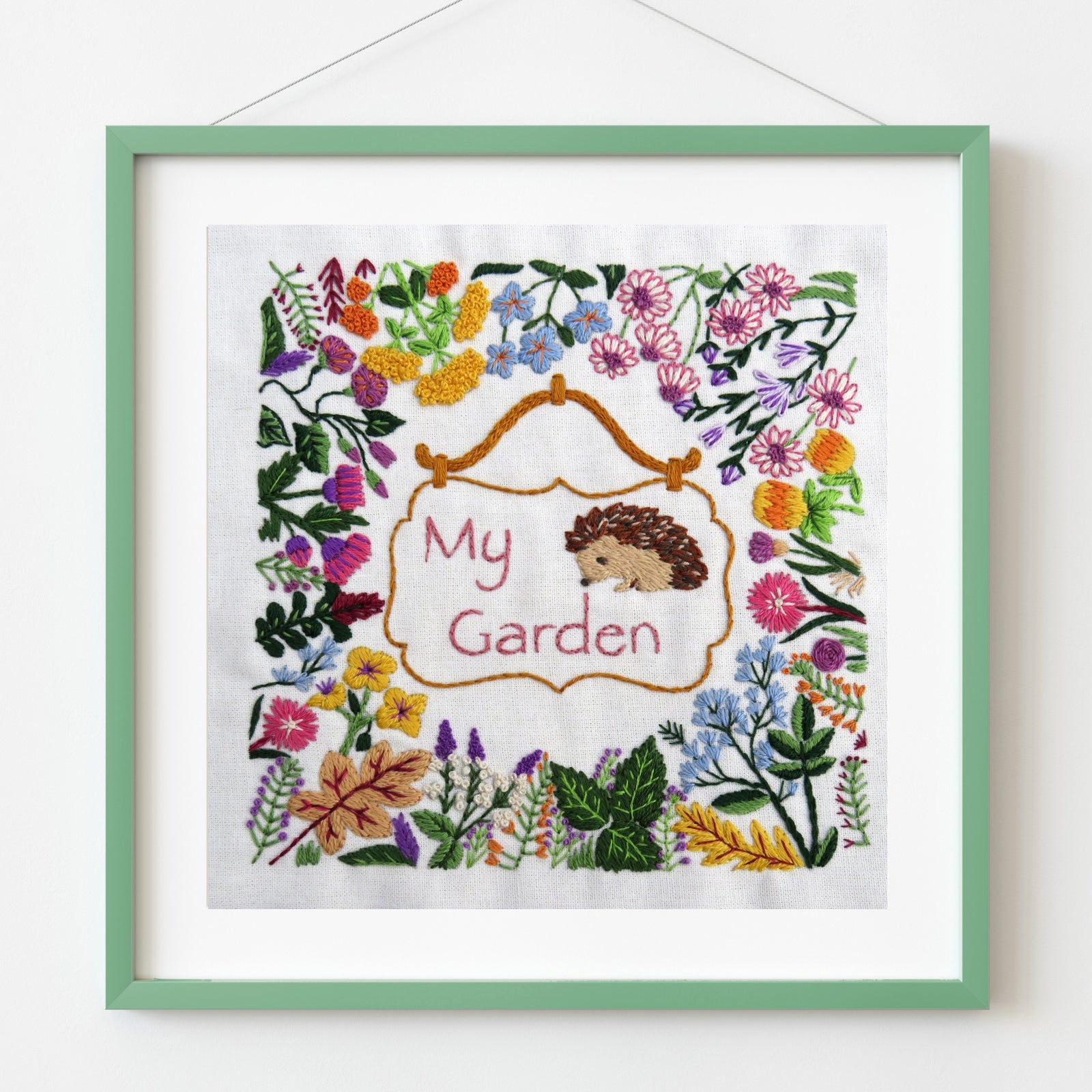 Embroidery with hedgehog and floral design in a green frame