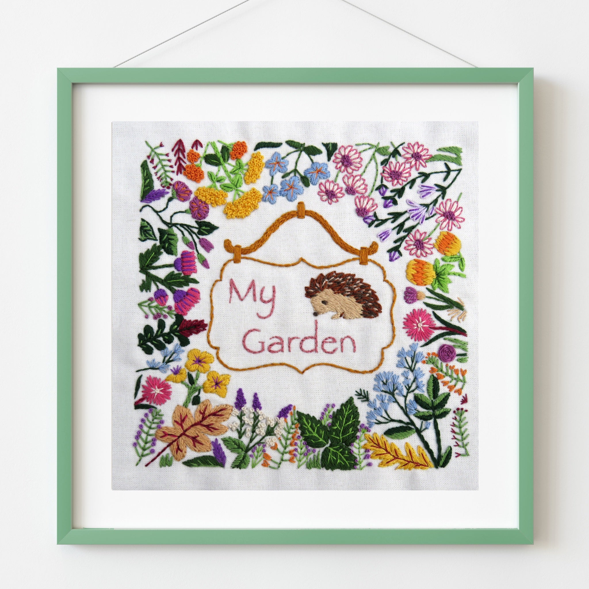 Embroidery with hedgehog and floral design in a green frame