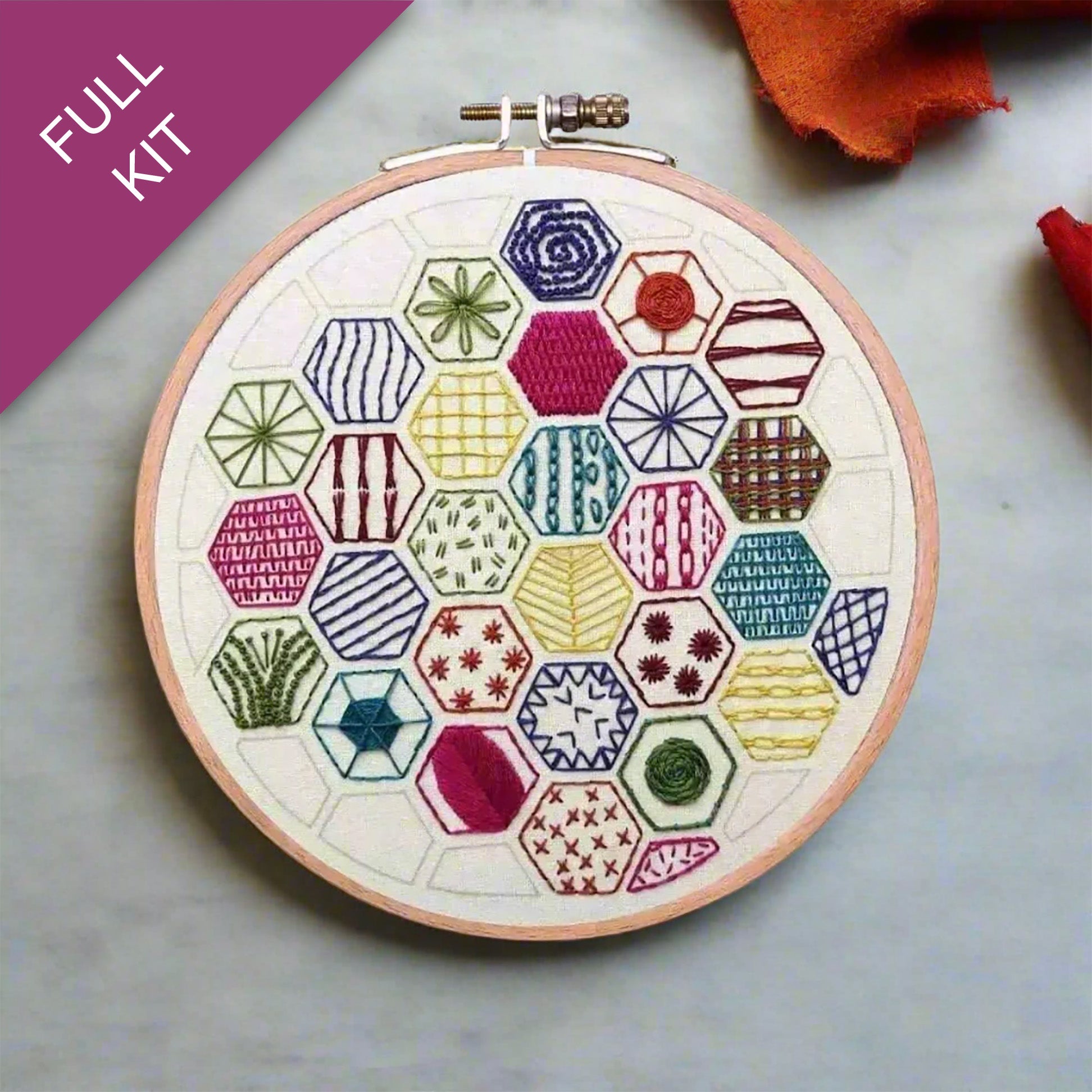 Embroidery hoop with colorful geometric pattern on a gray surface