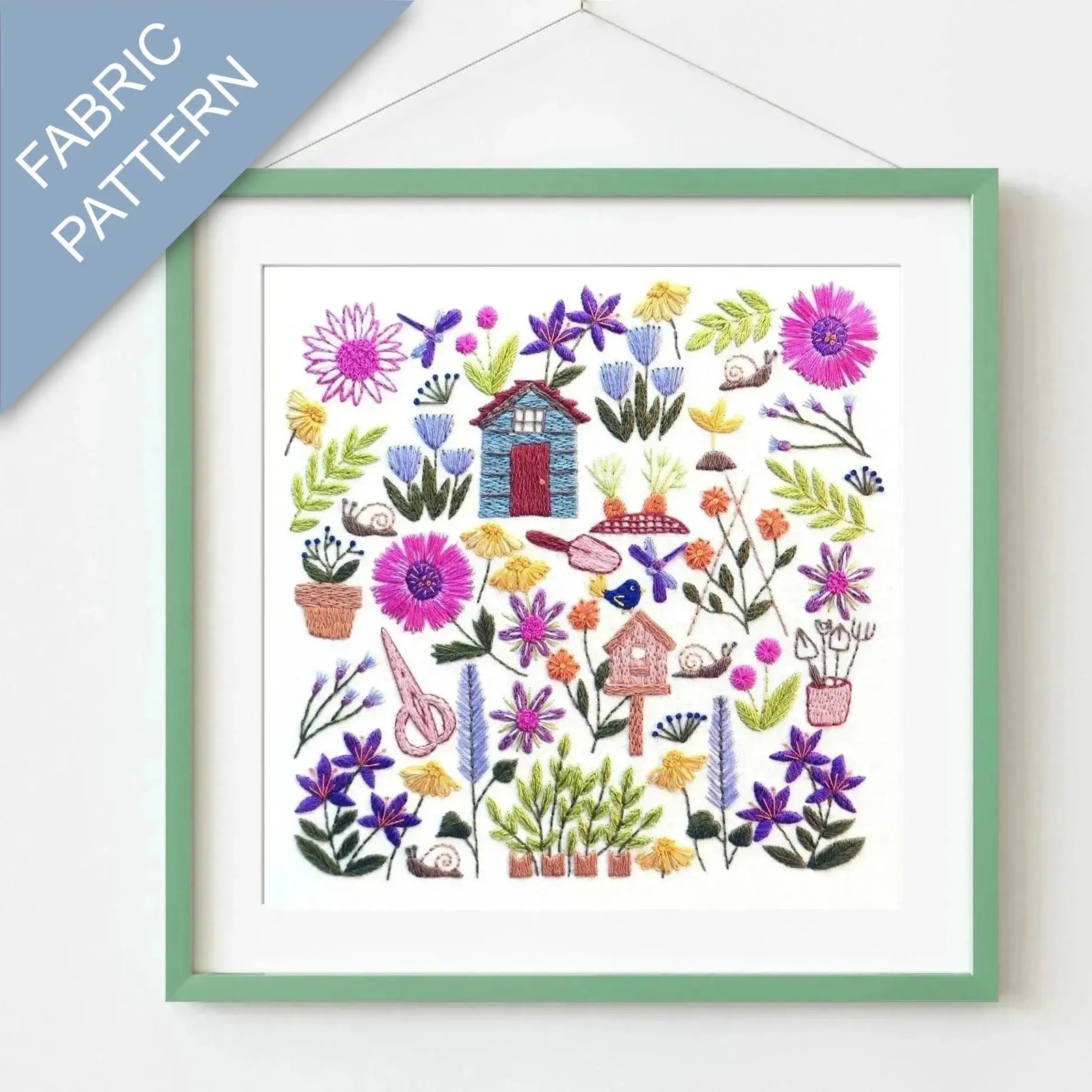 Framed fabric pattern with colorful flowers and small houses on a white background