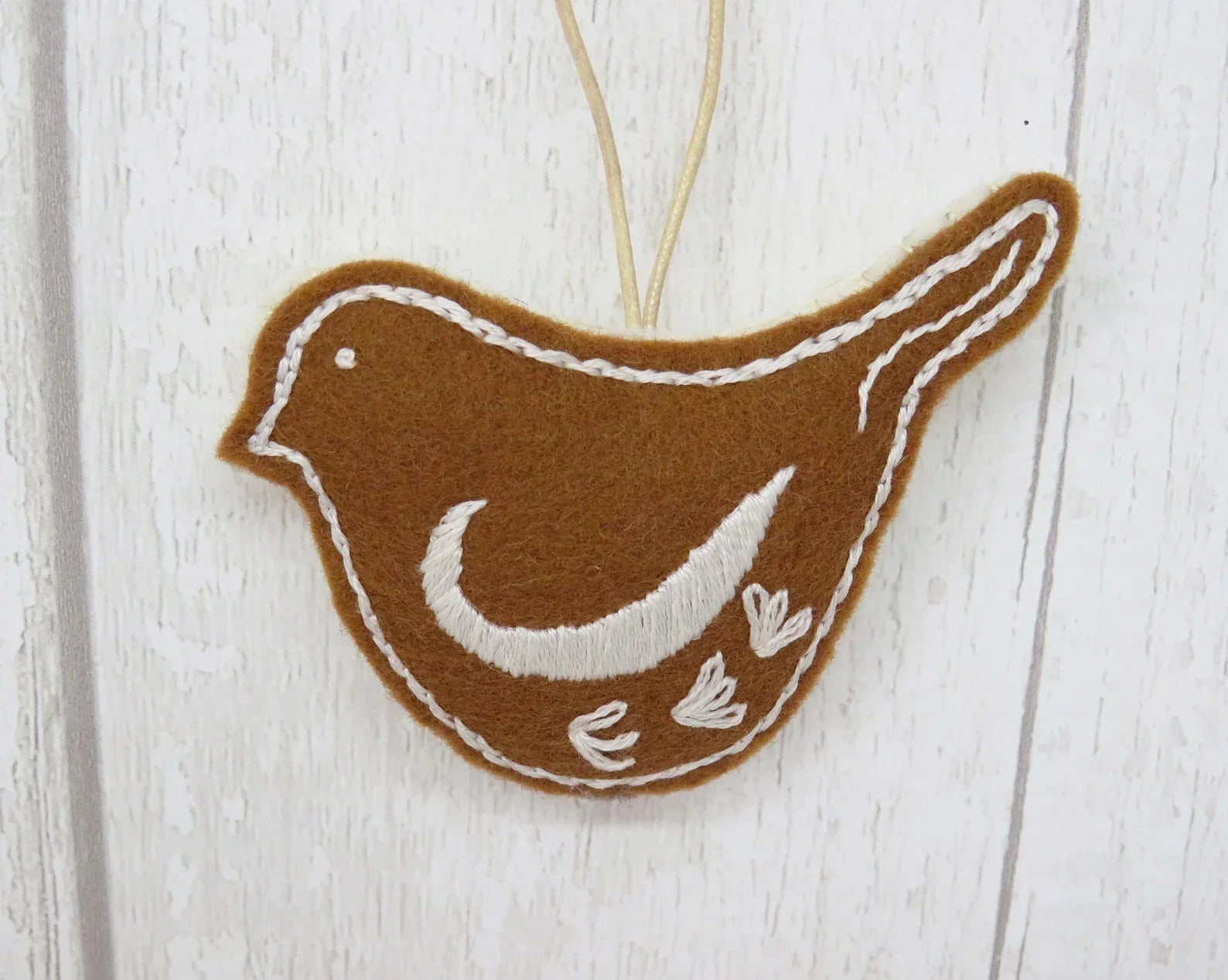 Brown and white bird-shaped ornament on a wooden surface