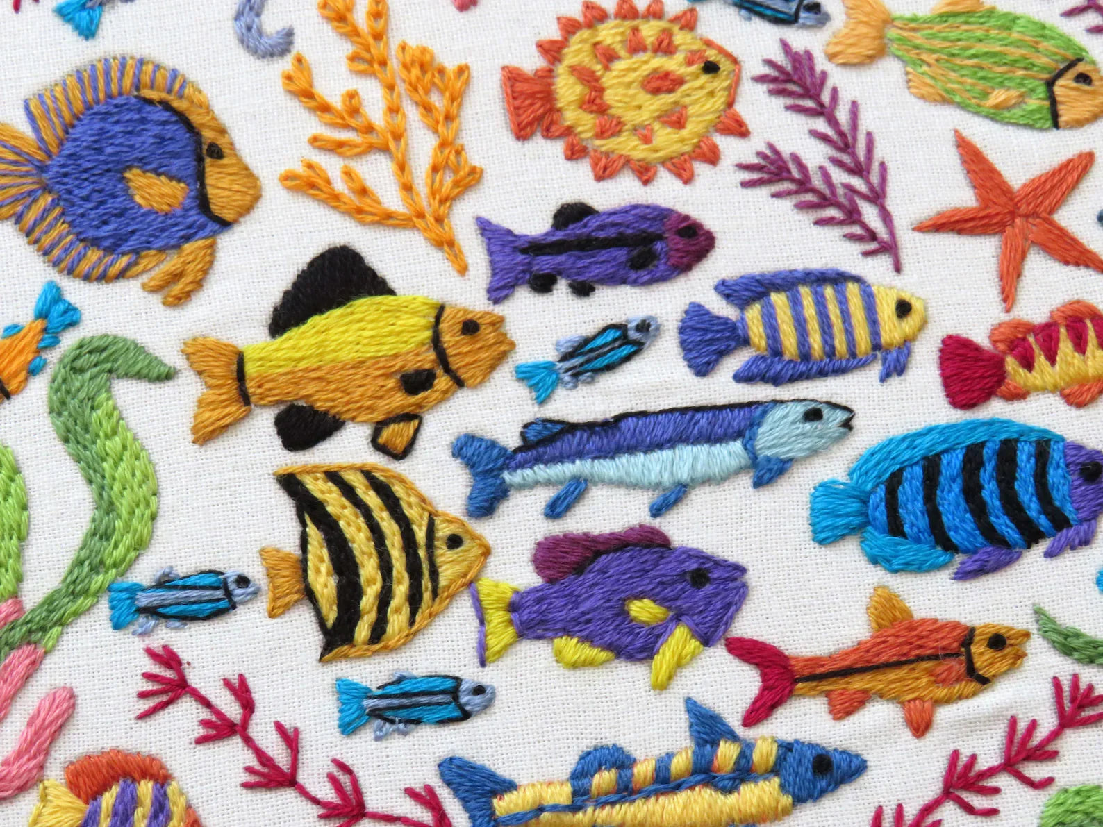 Embroidered pattern of colorful fish and sea creatures on a white background