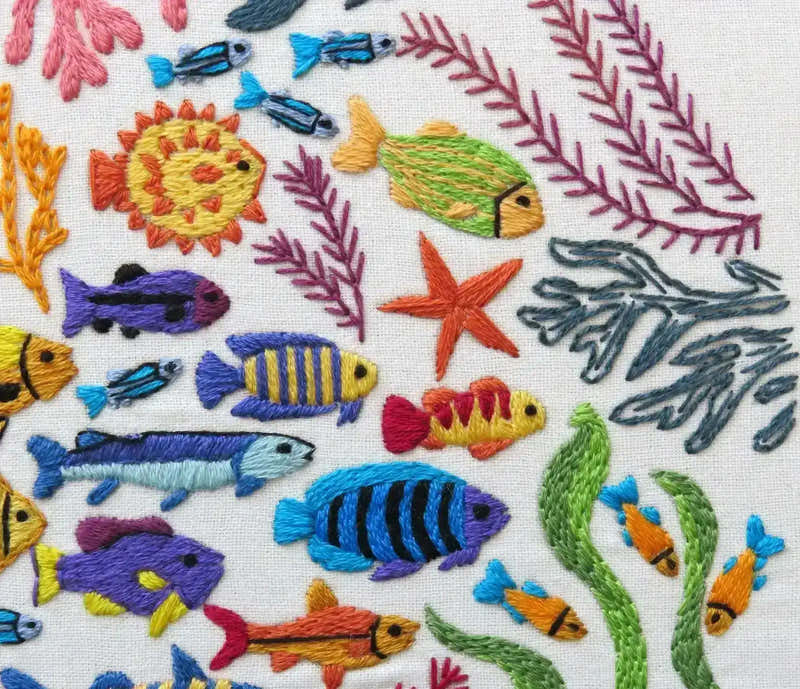 Embroidered pattern of colorful fish and sea plants on a white background