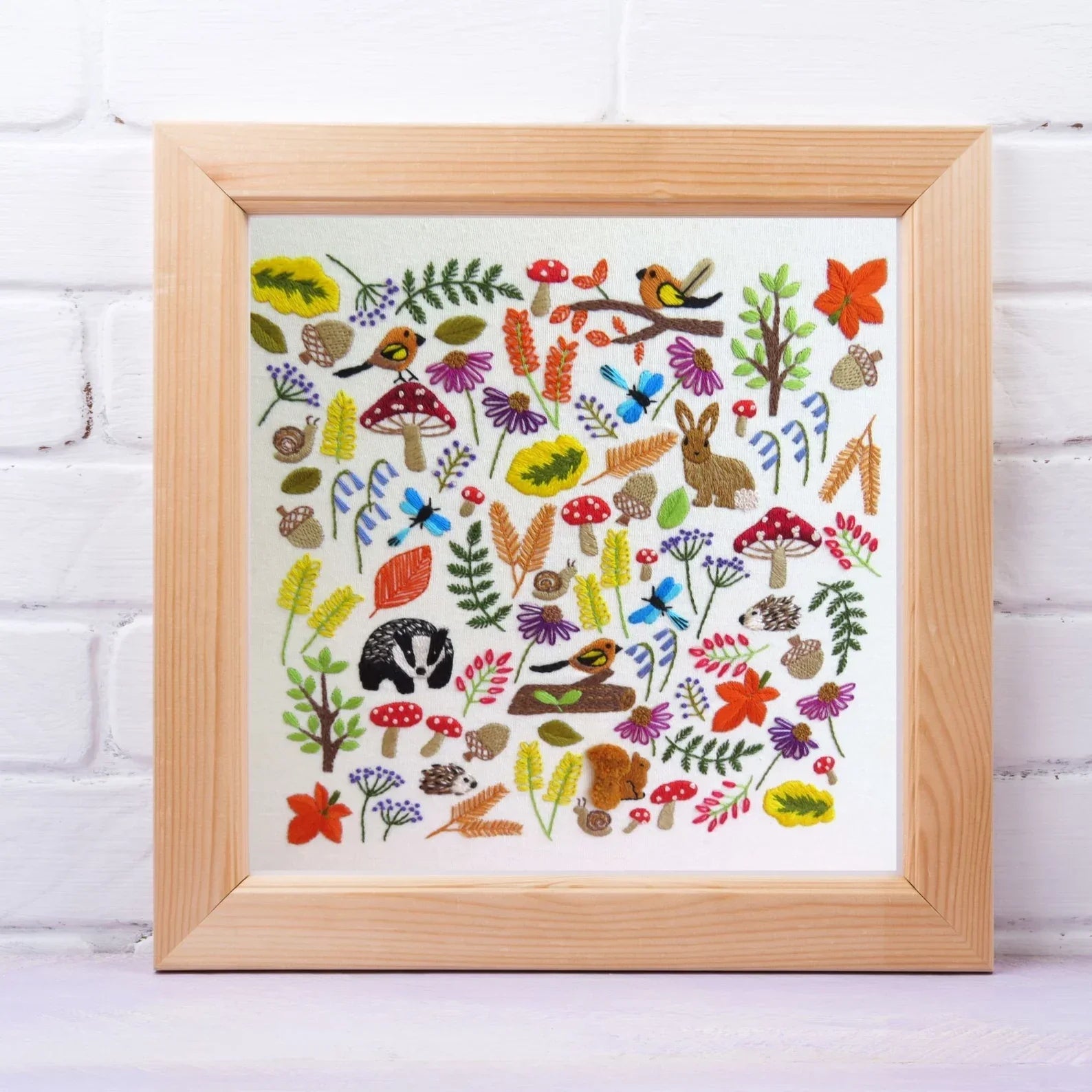 Framed artwork with colorful nature-themed design on a white brick wall background