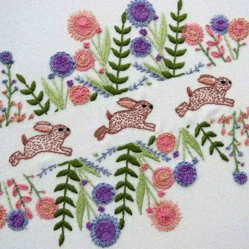 Embroidery design with rabbits and flowers on a white background