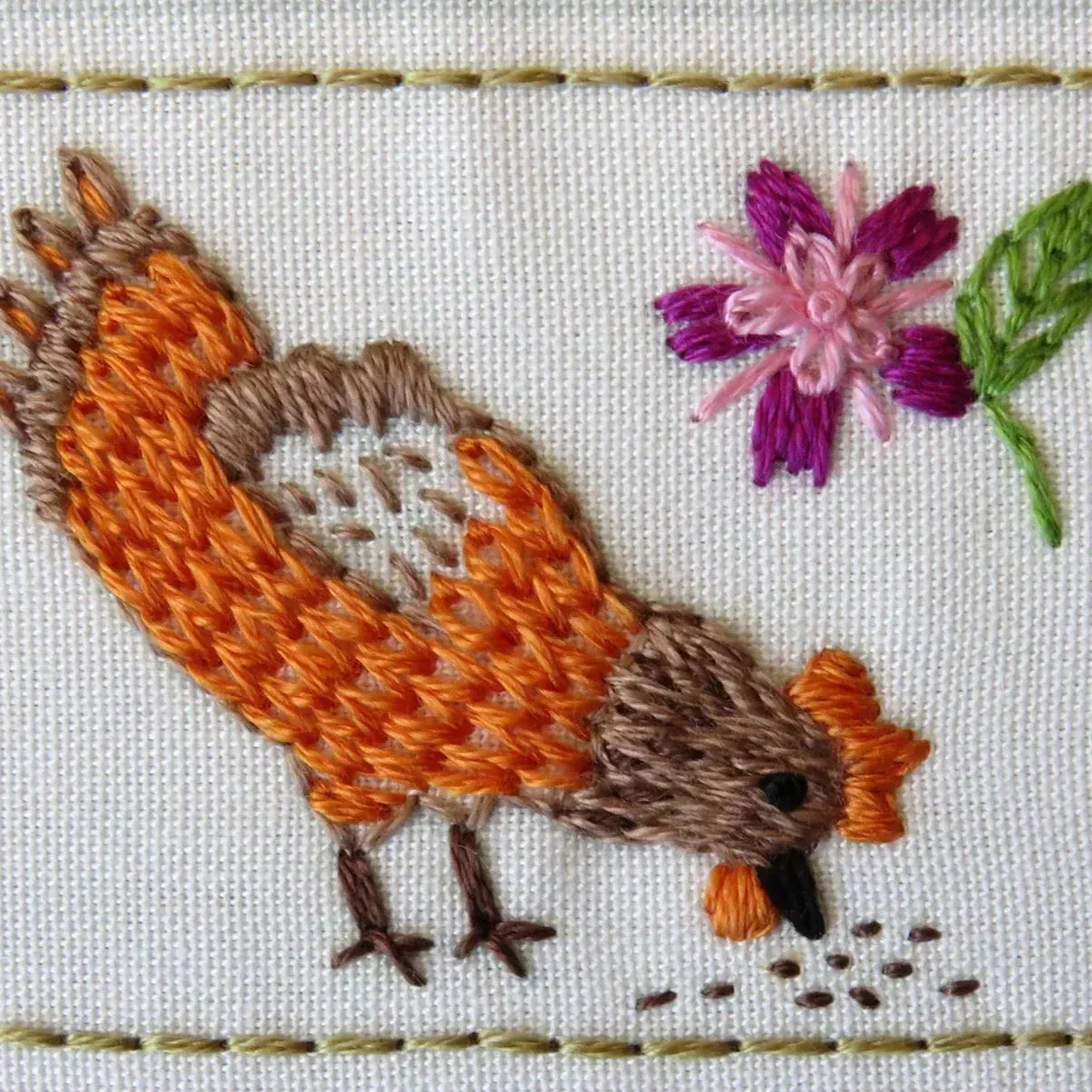 Embroidered design of a bird and flower on fabric