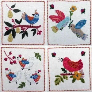 Four embroidered coasters with birds and floral designs on a white background