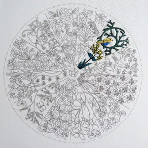 Coloring page with a mandala design featuring a bird and floral elements, partially colored.