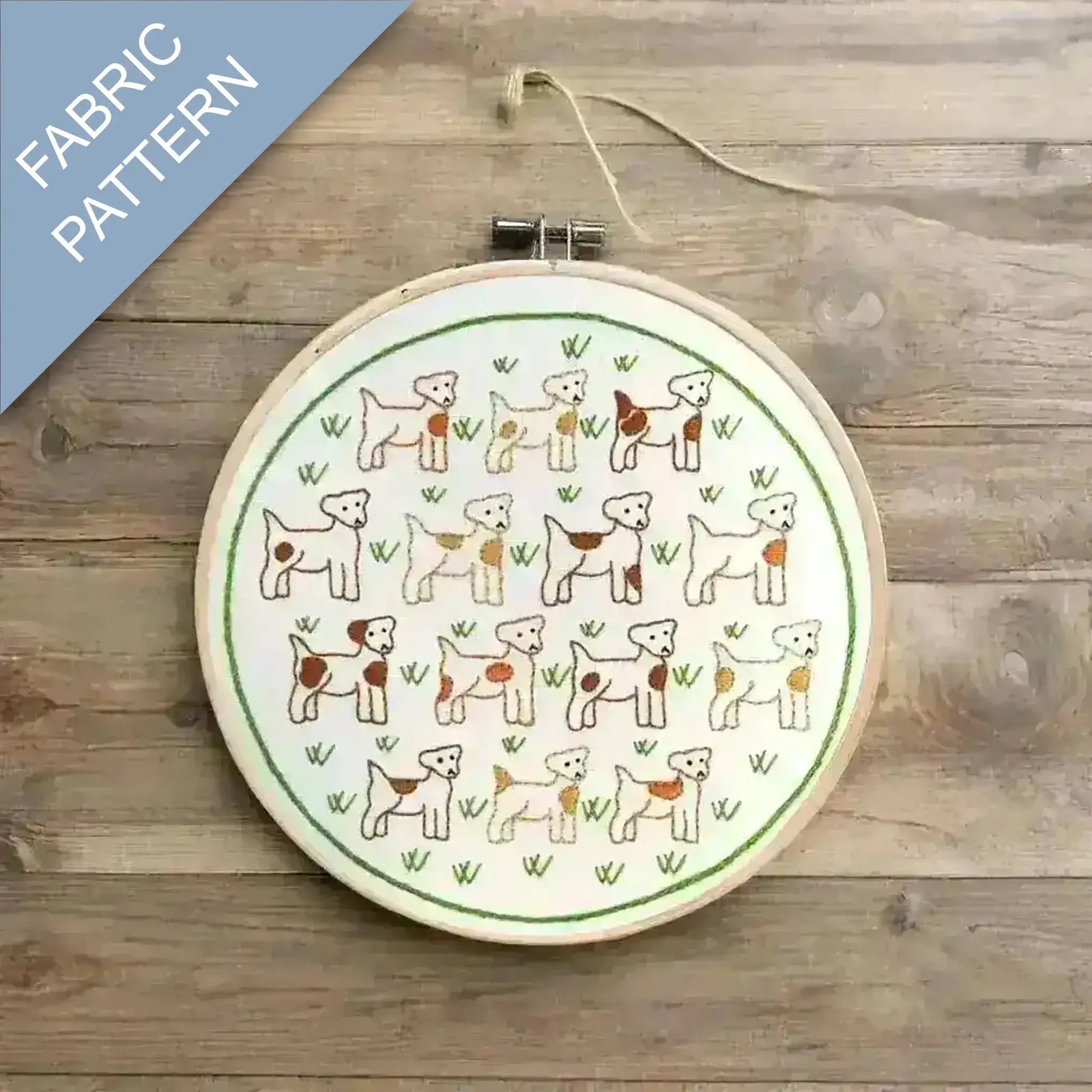 Embroidery hoop with dog pattern on fabric against a wooden background
