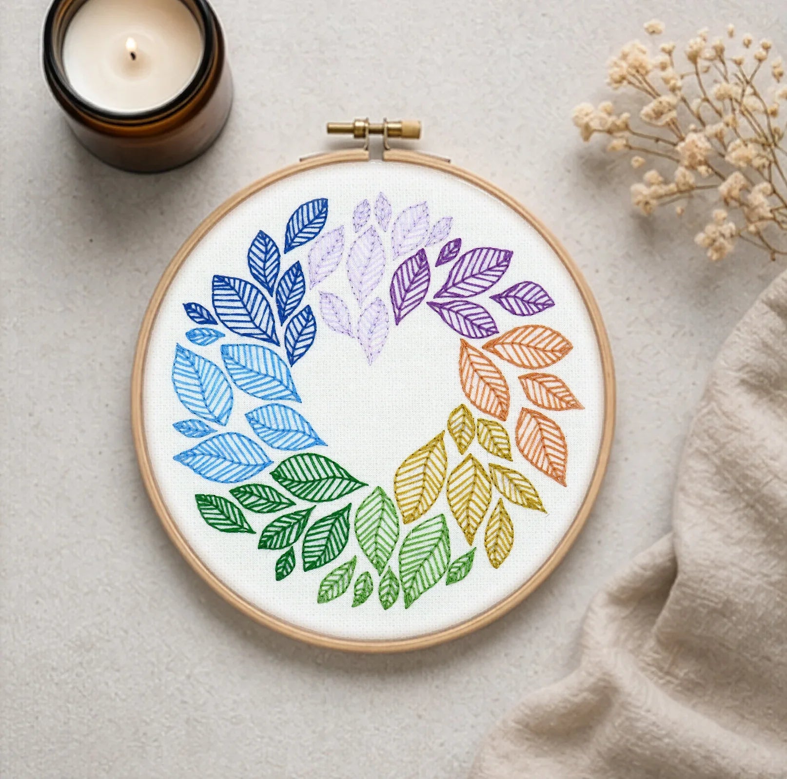 Embroidery hoop with colorful leaf pattern on a neutral background