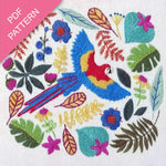 Embroidery design with a colorful parrot and floral patterns on a white background.
