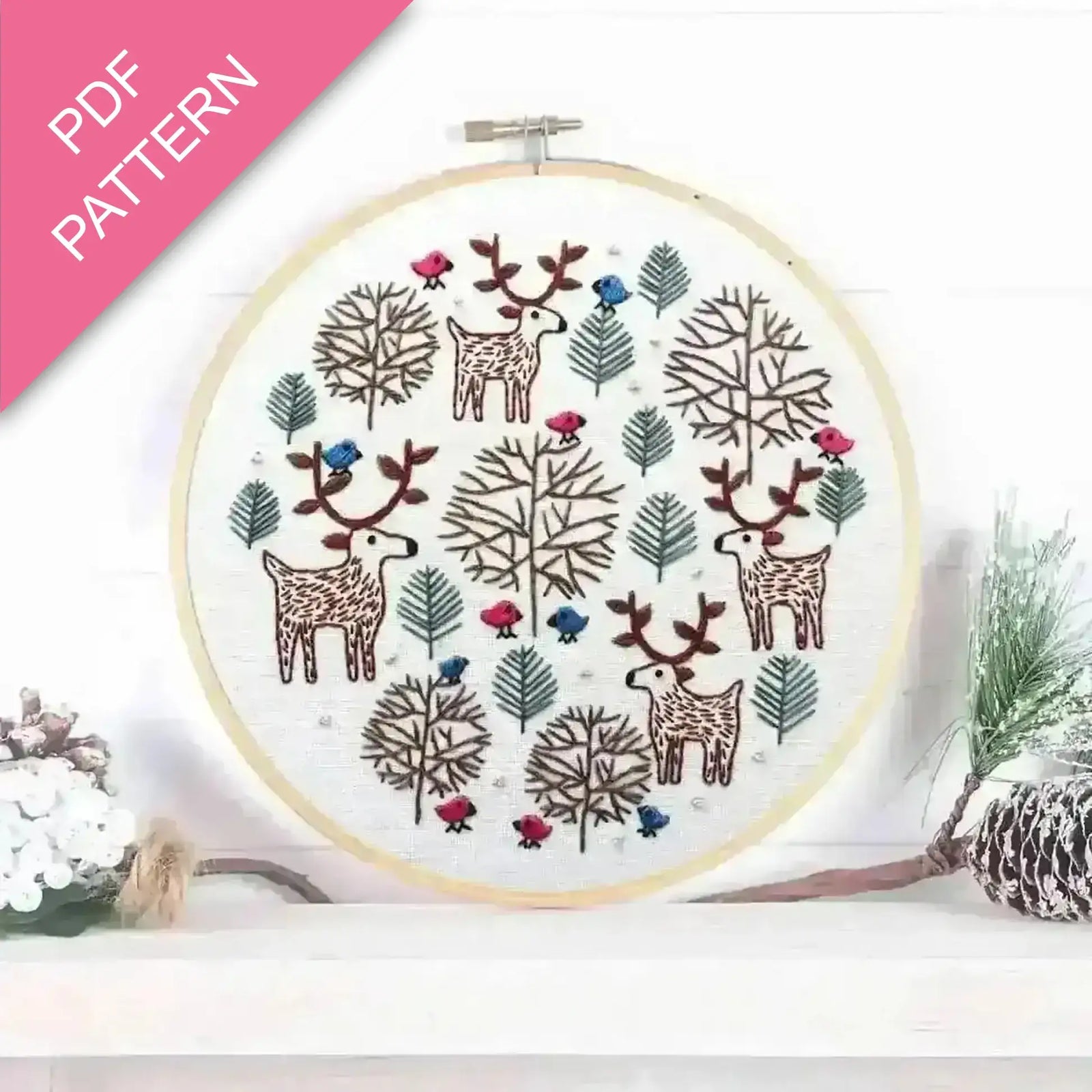 Embroidery hoop with Christmas deer and tree pattern on a white background