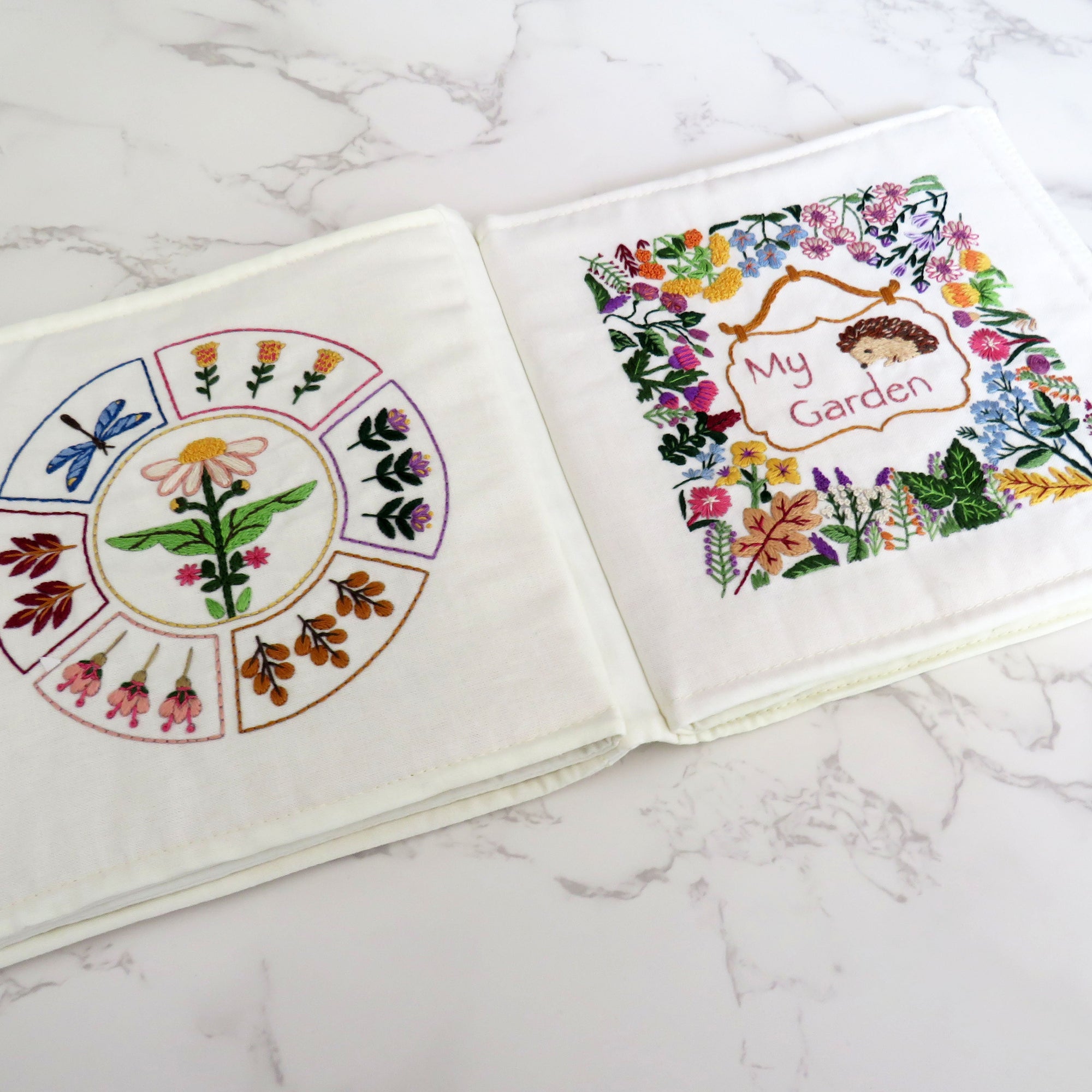 Two embroidered fabric panels with floral designs on a marble surface