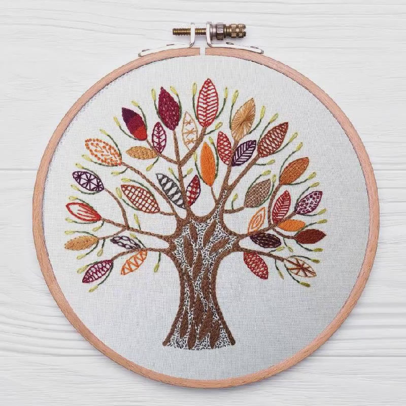 Embroidery hoop with a colorful tree design on a white background