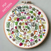 Embroidery hoop with colorful floral and animal pattern on a gray background