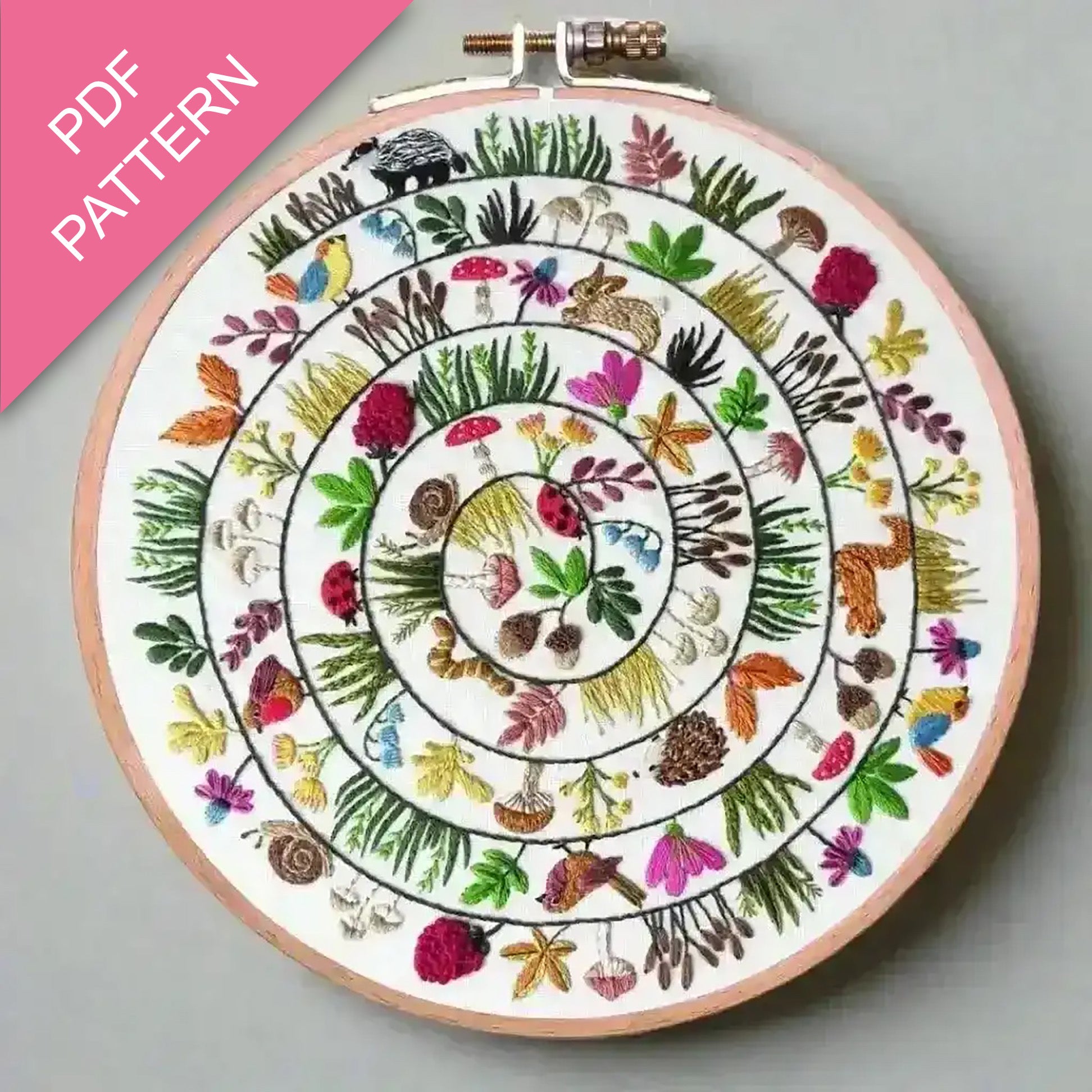 Embroidery hoop with colorful floral and animal pattern on a gray background