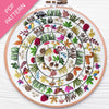 Embroidery hoop with a colorful circular pattern of animals and plants on a white background.