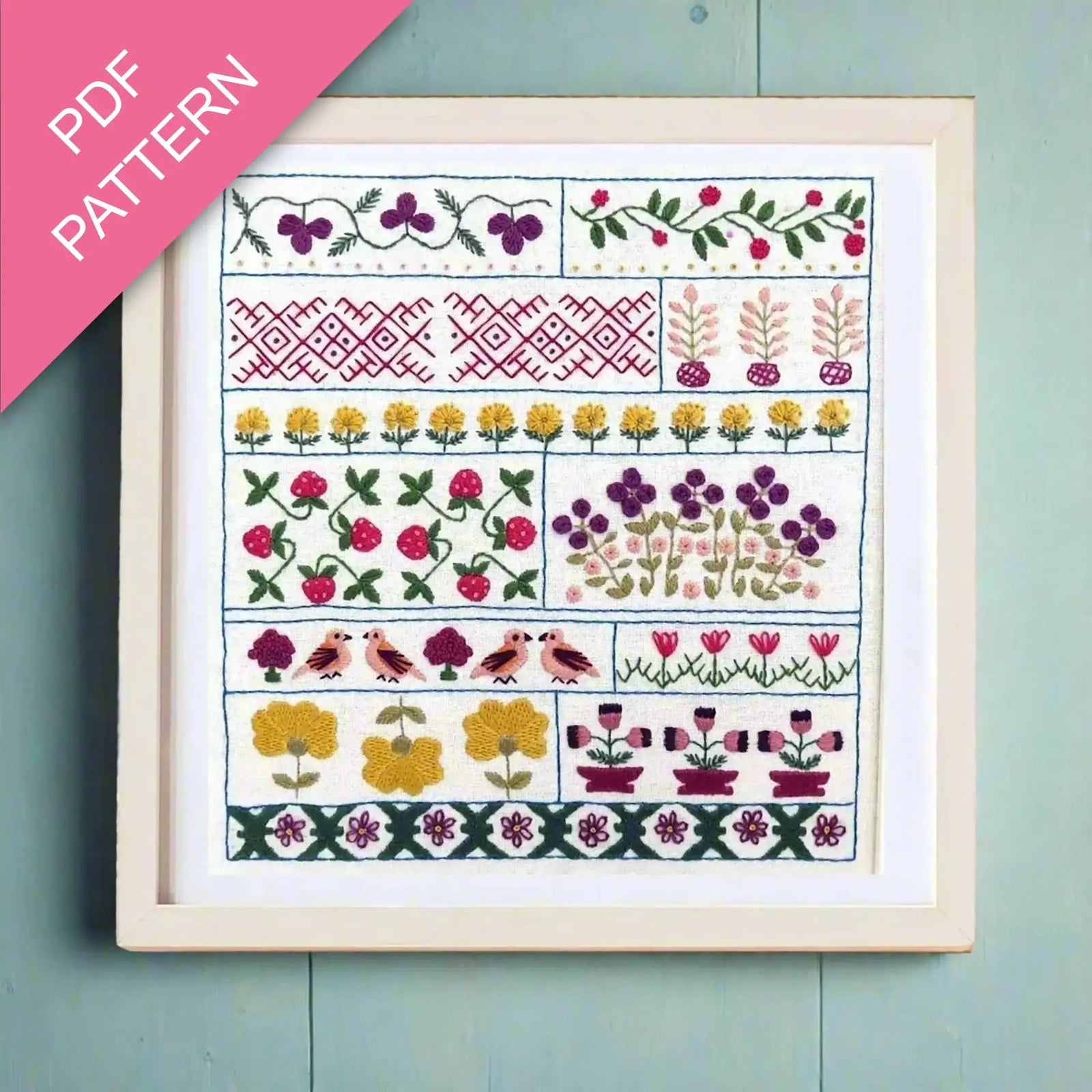 Framed cross-stitch pattern with floral and geometric designs on a teal background