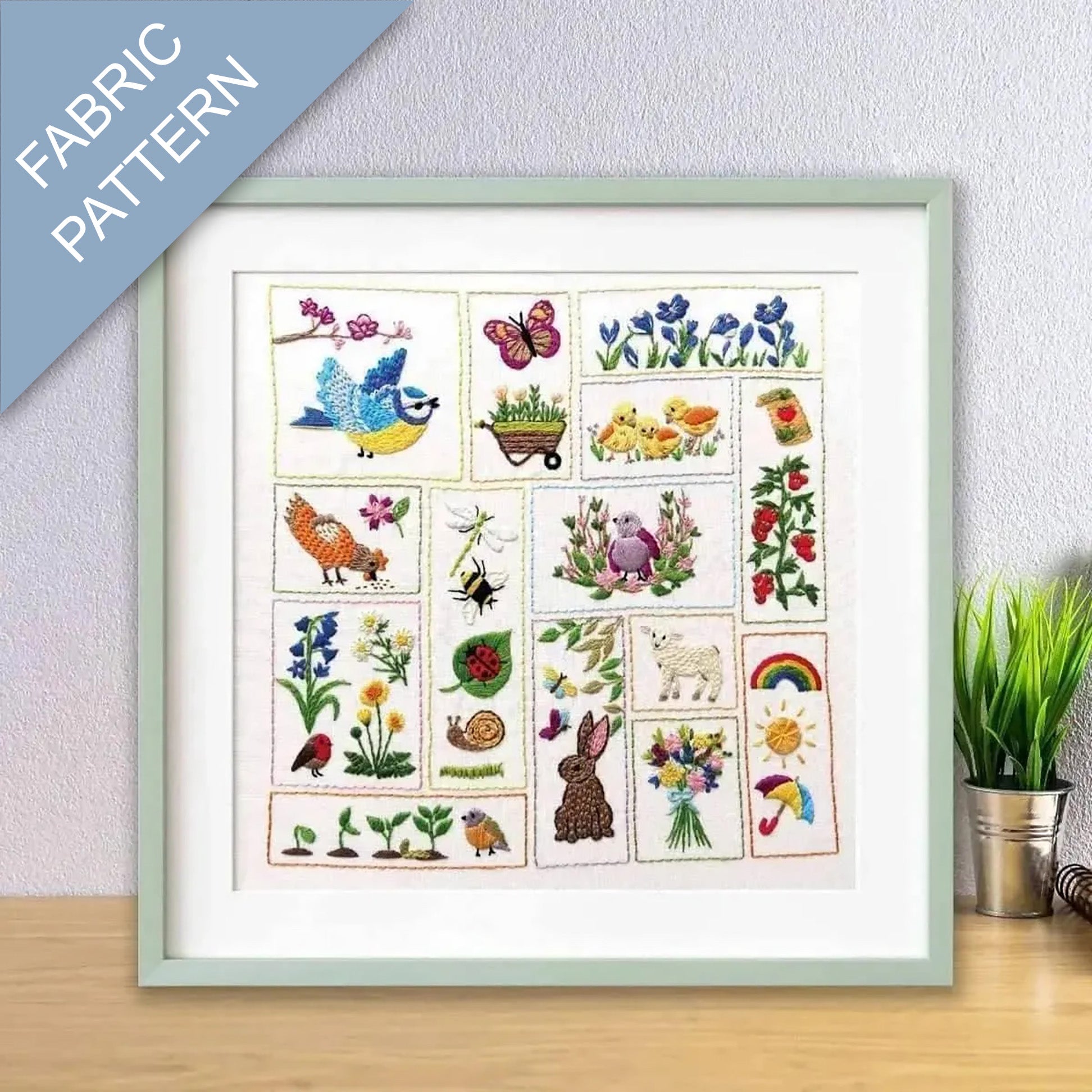Framed fabric pattern with colorful illustrations of nature-themed designs on a light gray wall.