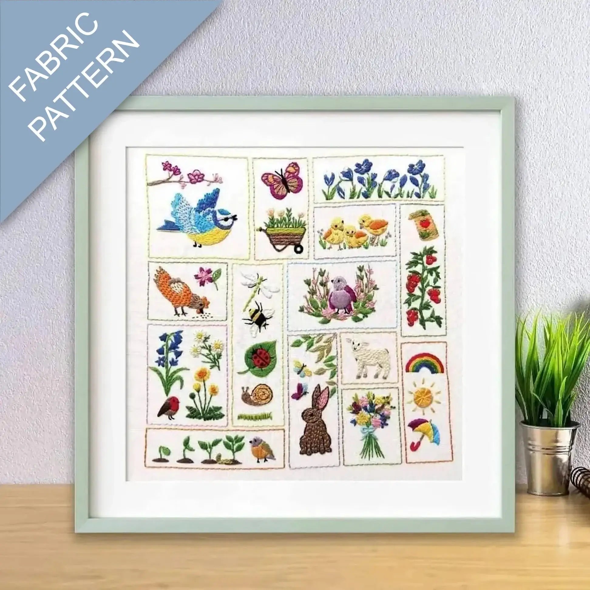 Framed fabric pattern with colorful illustrations of nature-themed designs on a light gray wall.