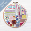 Embroidery hoop with colorful geometric pattern on a wooden surface