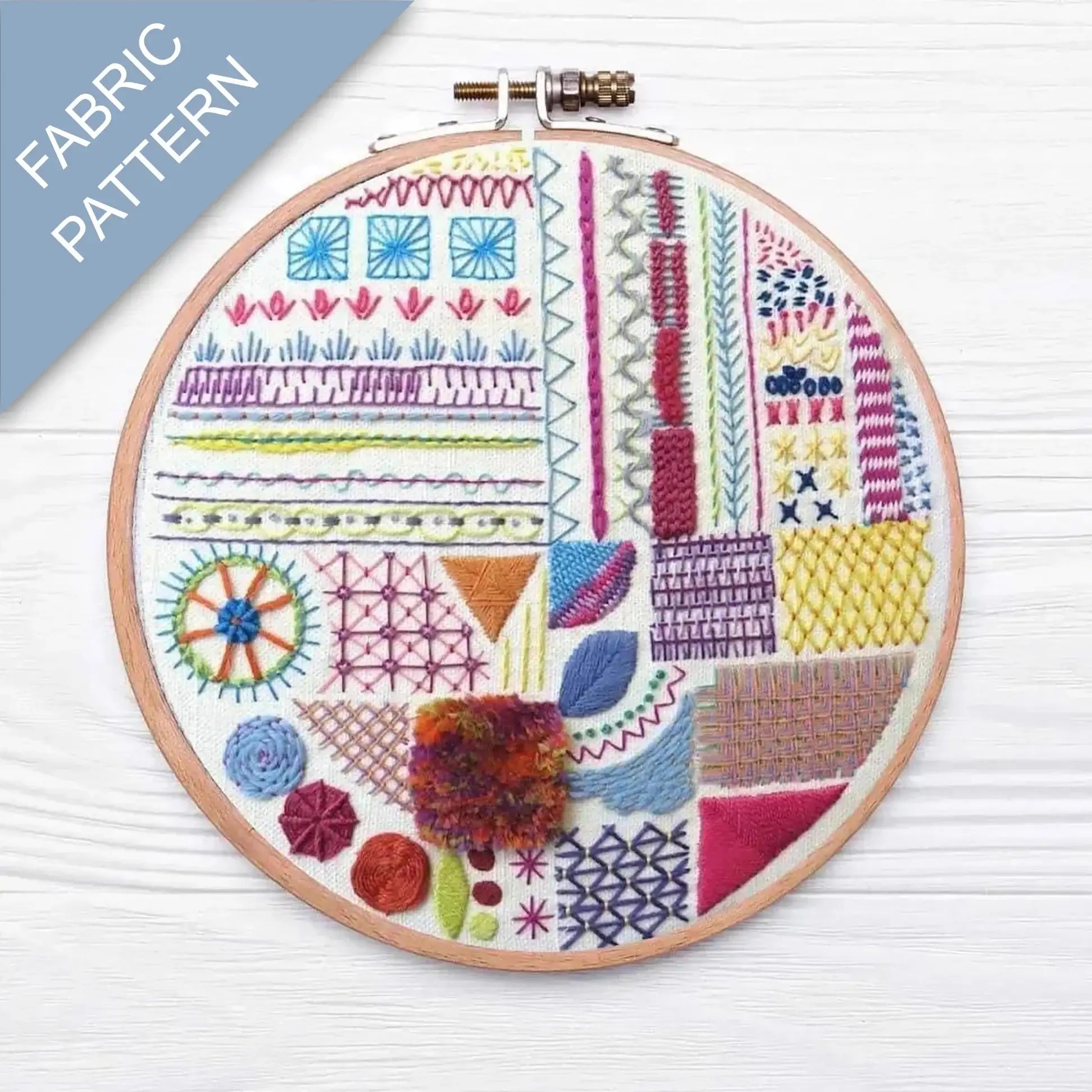 Embroidery hoop with colorful geometric pattern on a wooden surface