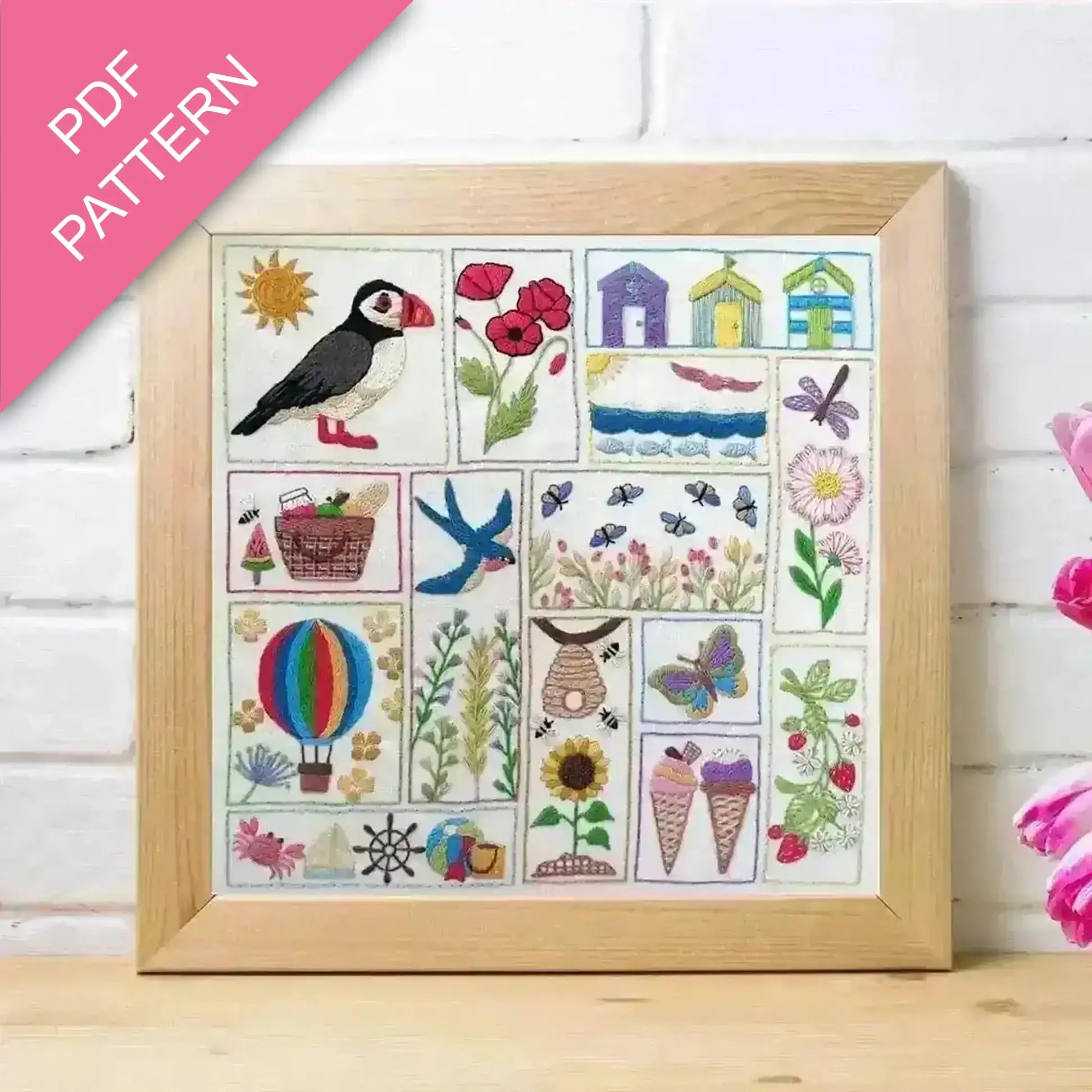 Framed cross-stitch pattern with puffin, flowers, and other elements on a white background.