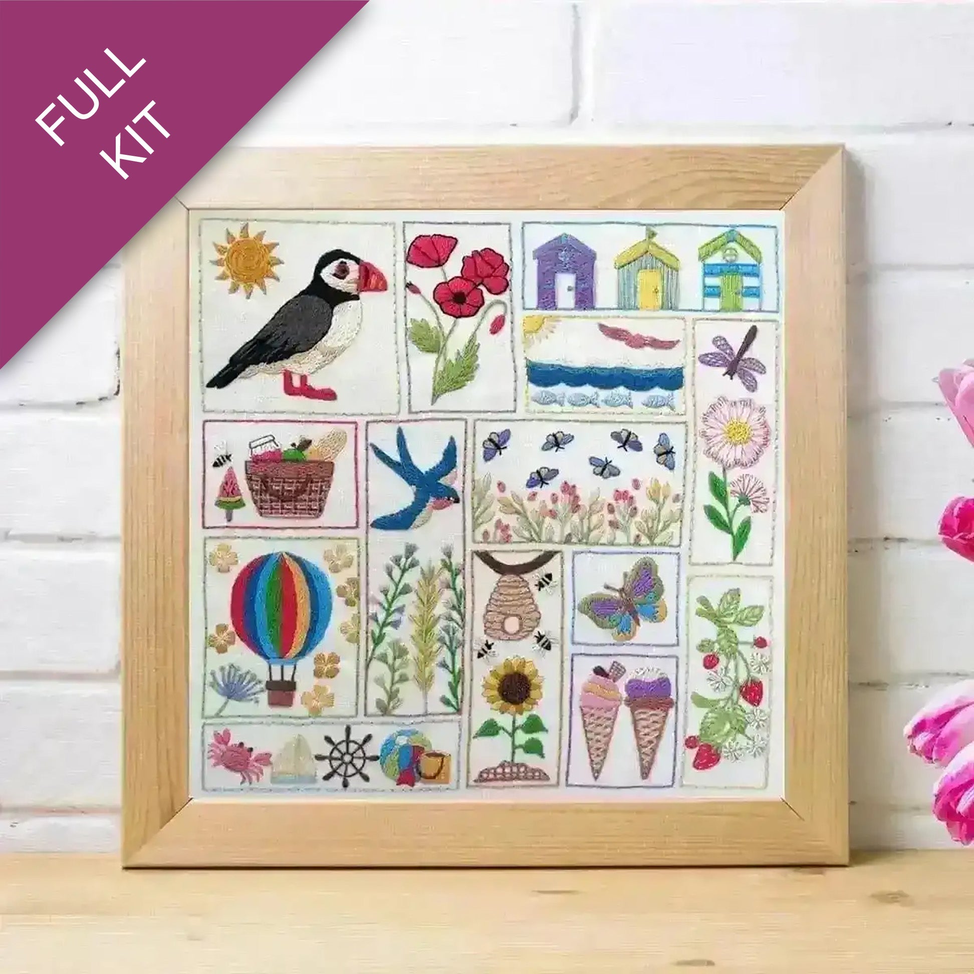 Framed cross-stitch kit with various designs including a puffin, flowers, and animals on a white background.