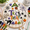 Embroidery hoop with Halloween-themed designs and 'Trick or Treat' text, surrounded by embroidery supplies.