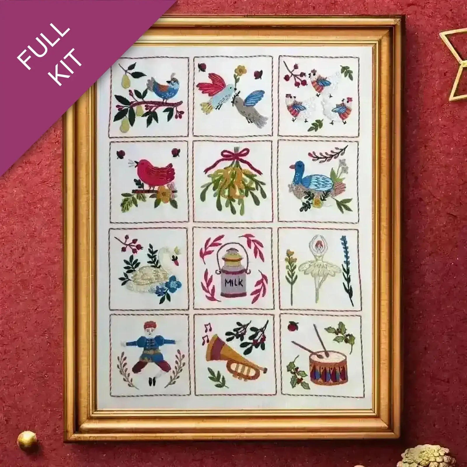 Framed cross-stitch kit with various designs on a red background