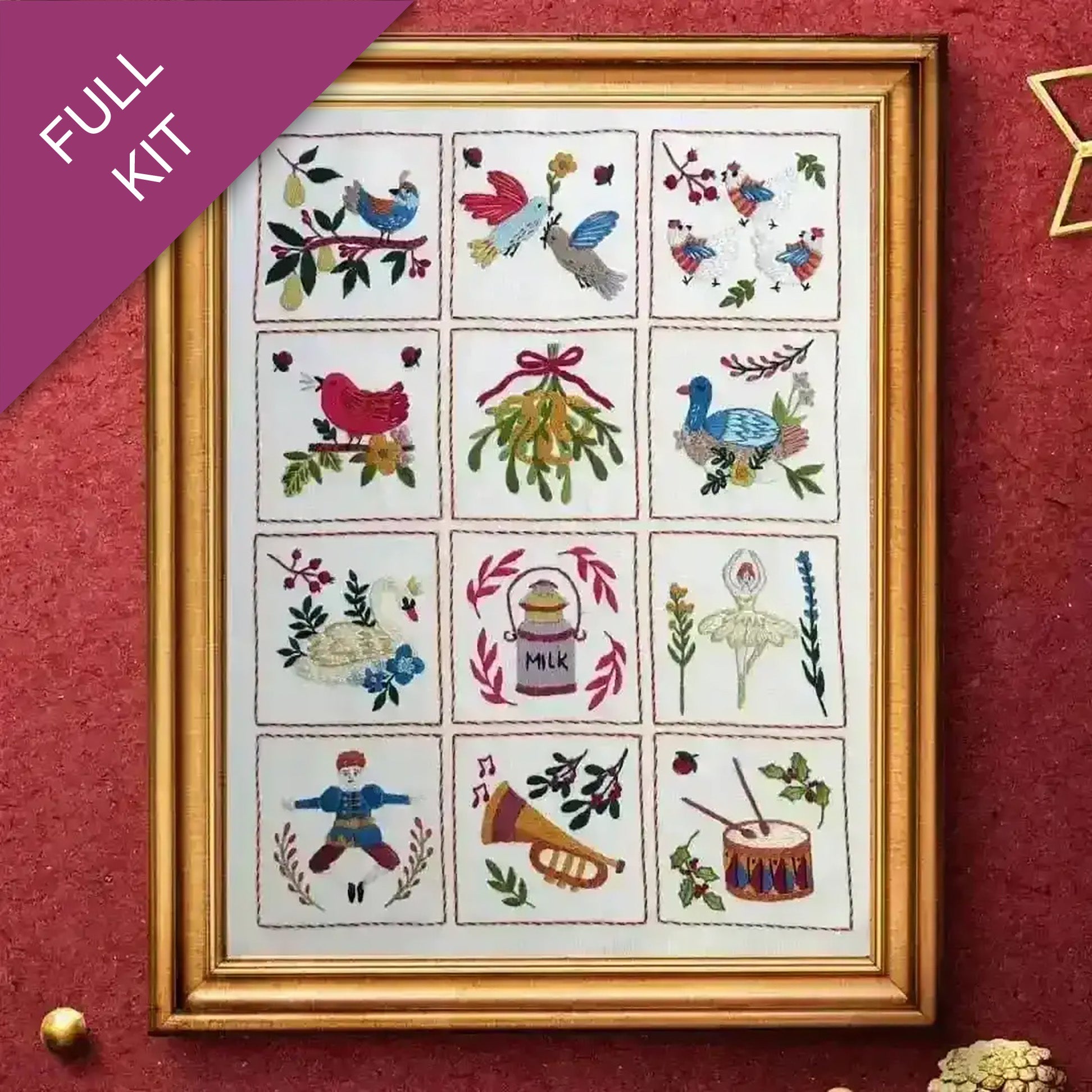 Framed cross-stitch kit with various designs on a red background