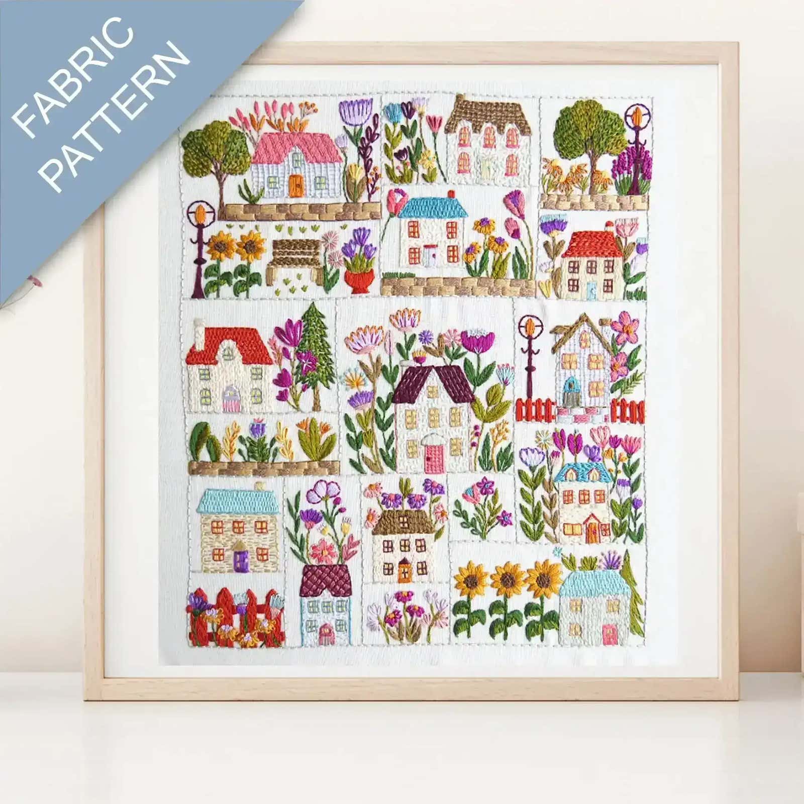 Framed fabric pattern with colorful houses and flowers on a white background