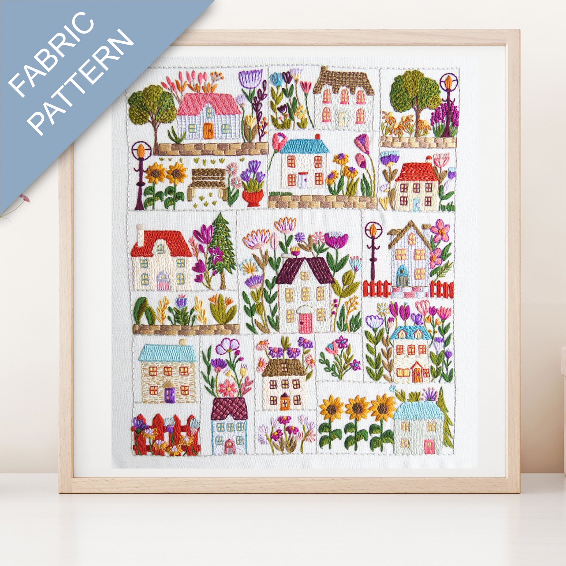 Framed fabric pattern with colorful houses and flowers on a white background