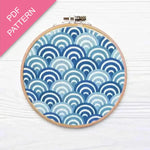 Embroidery hoop with blue and white wave pattern on a white background