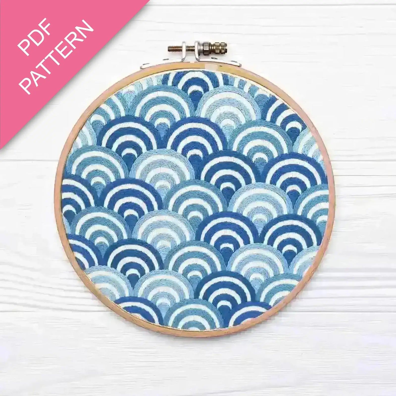 Embroidery hoop with blue and white wave pattern on a white background
