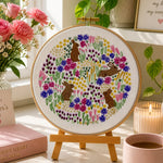 Decorative scene with a floral embroidery hoop, pink mug, and Mother's Day-themed items on a table.