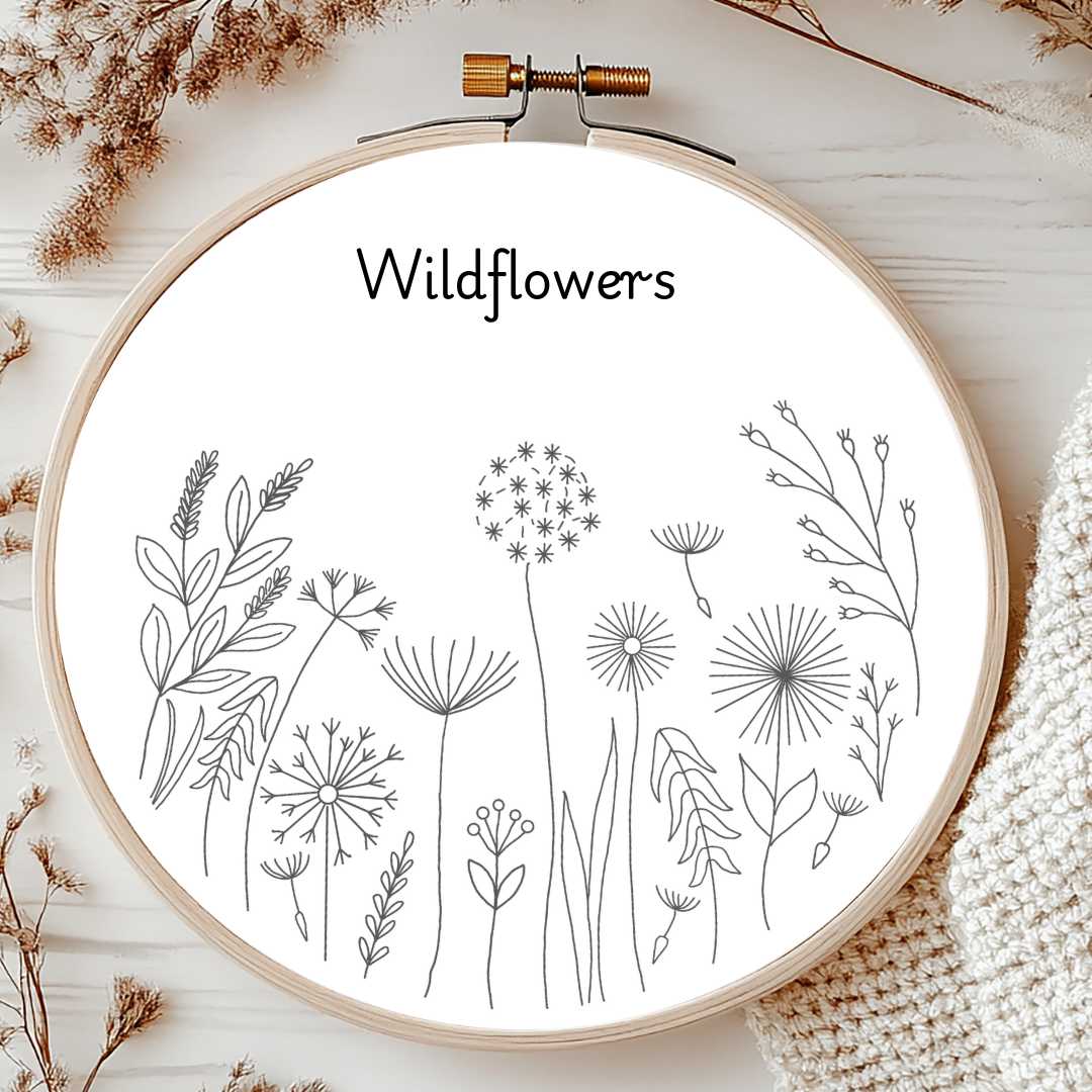 Embroidery hoop with wildflower designs and the word 'Wildflowers' on a wooden surface.