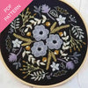 Embroidery hoop with floral pattern on black fabric, PDF pattern text overlay