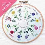 Embroidery hoop with floral design and months of the year text on a white background.