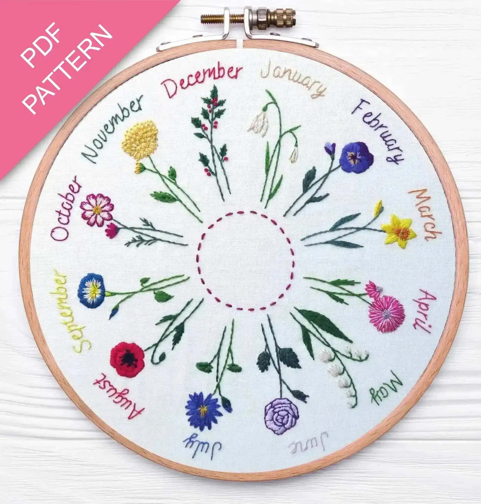 Embroidery hoop with embroidered flowers and months on a white background