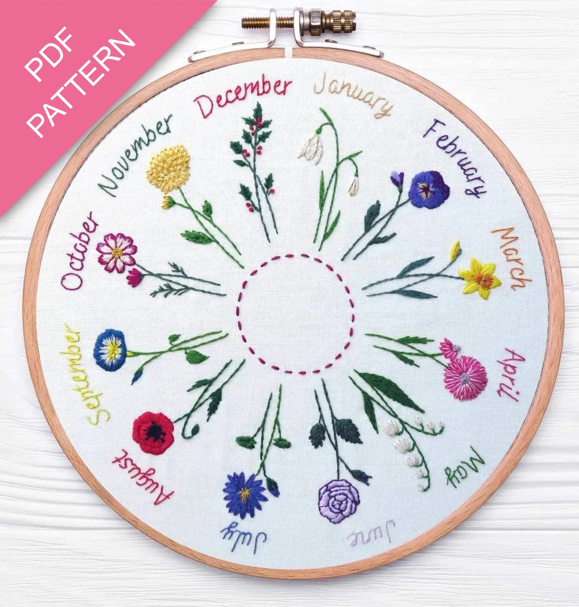 Embroidery hoop with embroidered flowers and months on a white background